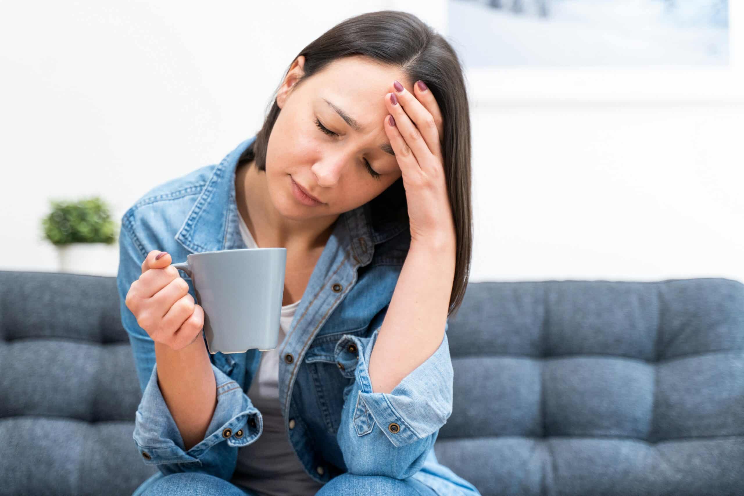 Stressed woman sitting on a couch with her hand on her forehead, symbolizing anxiety, emotional distress, and the importance of mental health support